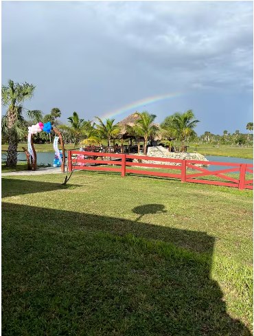 Rainbow over the property with red ranch fencing and the pavilion beyond