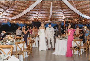 Wedding party gathered at round tables under the covered pavilion roof during the reception